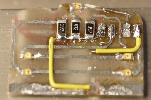 Een bestaand electronicaprintje met SMD-LEDs, SMD-weerstanden en twee gele, geïsoleerde draadjes die naar de andere kant van de print gaan