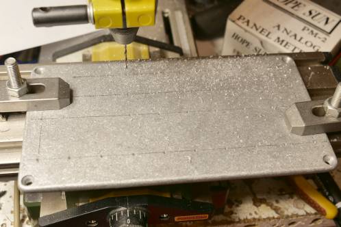 Een aluminium deksel gemonteerd op een kleine kruistafel om meerdere gaten te boren