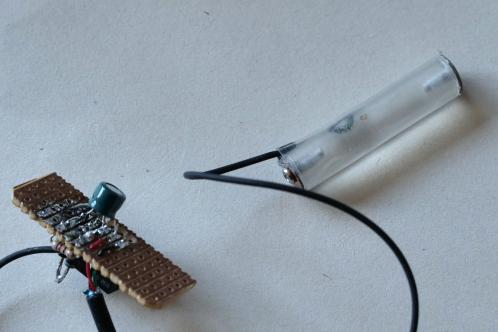 Een kleine elektronicaprintje, een stukje plexiglas rondstaf in krimkous en een paar elektronica-onderdelen