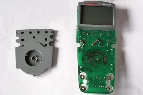 Een groene elektronicaprint met LCD-scherm en grijze kunststof sub-eenheid met draaibare contactschijf, twee hoofd-onderdelen van een Multimetrix DMM220 digitale multimeter