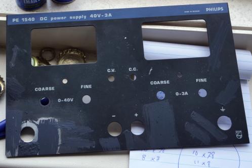 Een donkergrijze plaat met diverse witte markeringen voor stroom, spanning en regeling daarvan, een Philips PE1540 labvoeding-frontplaat
