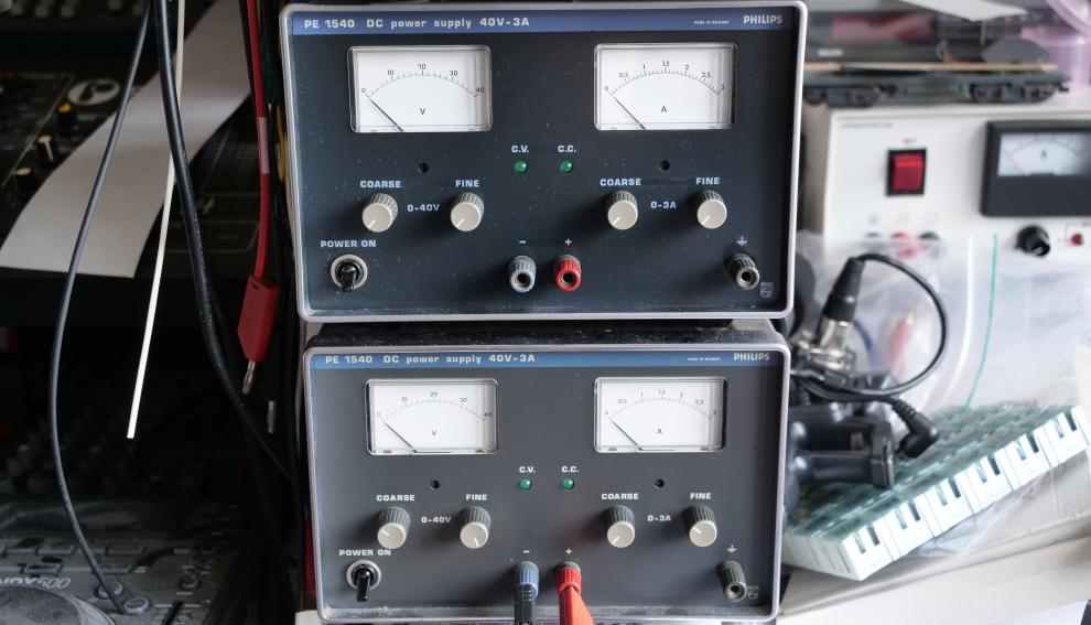 Twee elektronica-apparaten met donkergrijze frontplaat en blauwe band ter apparaat-identificatie bovenop elkaar, twee Philips PE1540 voedingen