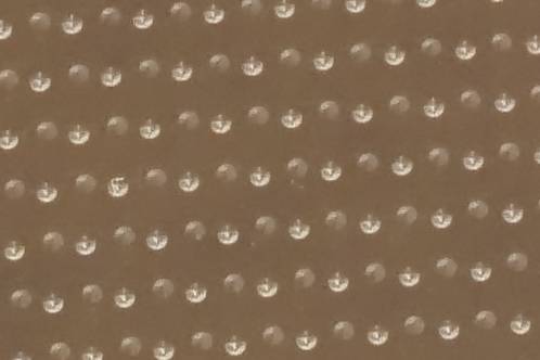 Een duizelingmakend patroon van gelaserde putjes in een acryl lichtgeleiderplaat, om het licht naar onderen te reflecteren
