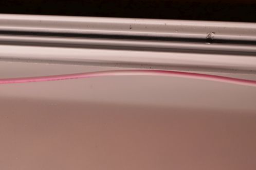 Een roze/wit verkleurde rode draad, onder invloed van UV-straling