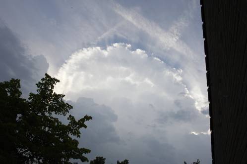 Een cumulonimbus met de duidelijke vorm van een atoomwolk hangt dreigend zichtbaar bij Purmerend in de buurt, terwijl de zon een stralenkrans om de wolk heen projecteert