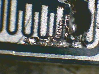 Kapotte transistorchip met breuk en vreemde soort corrosie, bekeken onder de microscoop