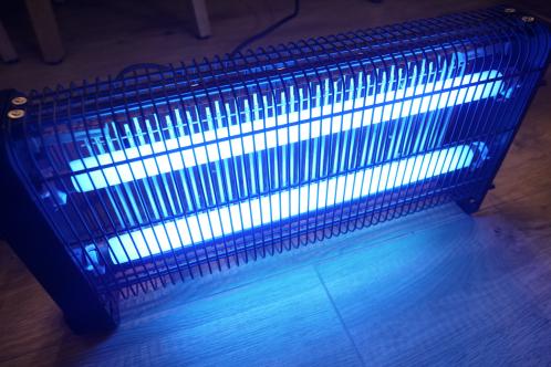 Een rooster, hoogspanningsrooster van een vliegenlamp, met aan de binnenzijde daarvan twee blauw verlichte UV TL-buizen na reparatie van de TL-buis module