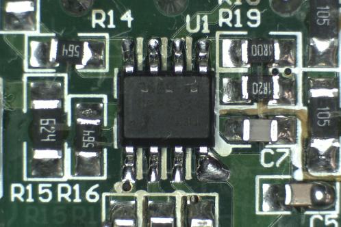 Een microscoopfoto van een groene elektronicaprint waar een nieuw IW3689-01 SOIC-8 IC volledig gesoldeerd is en de fluxresten verwijderd zijn met alcohol