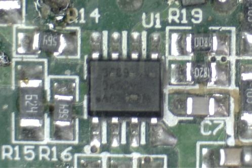 Een microscoopfoto van een groene elektronicaprint met SMD-weerstanden en condensatoren en een IW3689-01 SOIC-8 IC
