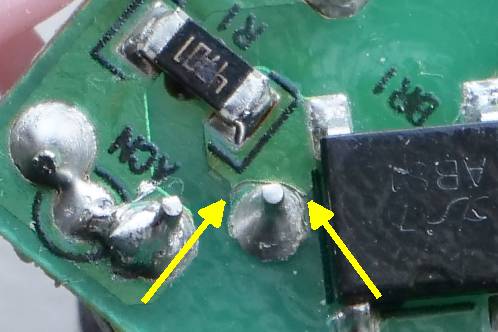 The green bottom-layer of an electronic circuitboard, with a cut in a PCB-trace and a slightly cooked SMD-resistor