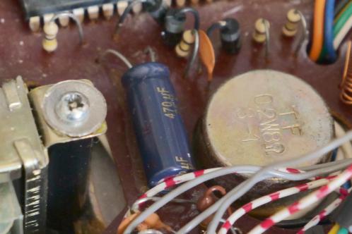 Een bruine elektronicaprint met meerdere draden, onderdelen en een cilindrisch, blauw onderdeel, een Panasonic FC elco van 470 uF ter vervanging van de oude
