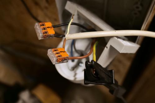 Een rood CEE-form stopcontact is geopend om 2 fasen te kunnen lenen voor het testen van de gerepareerde kachels. Twee lasdoppen met oranje hendels zijn gebruikt om te verbinden met de rigide draden uit het stopcontact