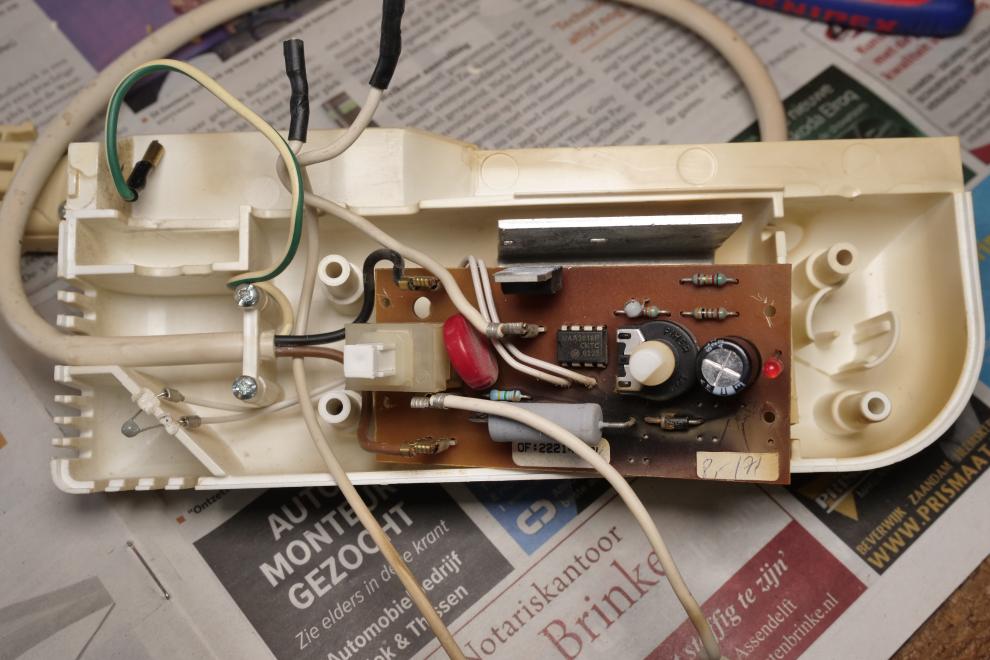 Een wit kunstof kastje met daarin een bruine elektronicaprint met diverse halfgeleiders, weerstanden en een enkele condensator ter regeling van een elektrische kachel