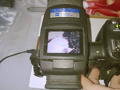 Sony DSC-R1 met gebarsten LCD-scherm na val van de trap, waarbij videolampje met de hoek insloeg op het scherm